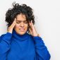 young hispanic woman with curly hair wearing turtleneck sweater with hand head headache because stress 85x85